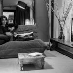 foto van een vrouw die zittend op een bank tv kijkt in de eerste verdieping flat van aplace antwerp ingericht in een warme bohemian chic stijl