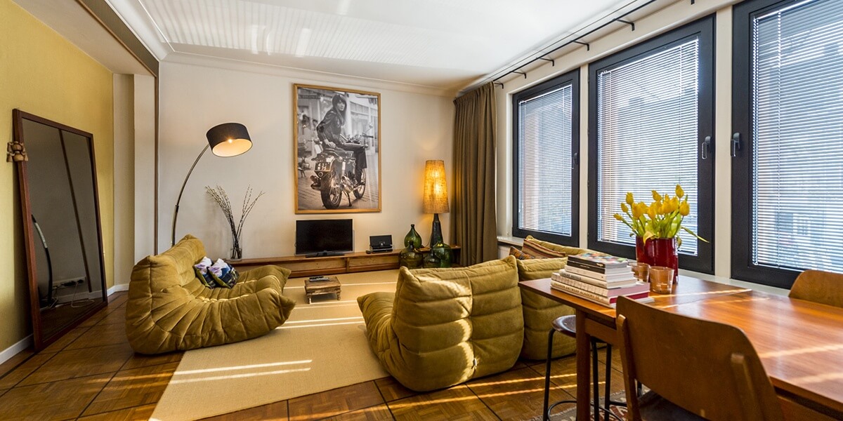 woonkamer ingericht in een warme – bohemian chic – stijl met banken, grote spiegel en lampen in de eerste verdieping flat van aplace antwerp