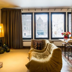 woonkamer ingericht in een warme – bohemian chic – stijl met bank, eetkamer en uitzicht op de vrijdagmarkt op de eerste verdieping flat van aplace antwerp