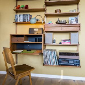 retro bureau met planken waarop platen met platenspeler staan en boeken